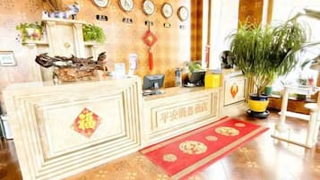 Un mostrador de recepción con una computadora, una planta y una alfombra roja.