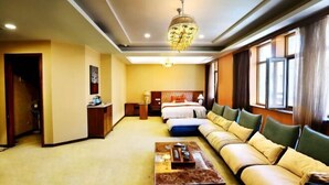 Une chambre d’hôtel équipée d’un canapé-lit, d’une table basse, d’un bureau et d’un lustre.