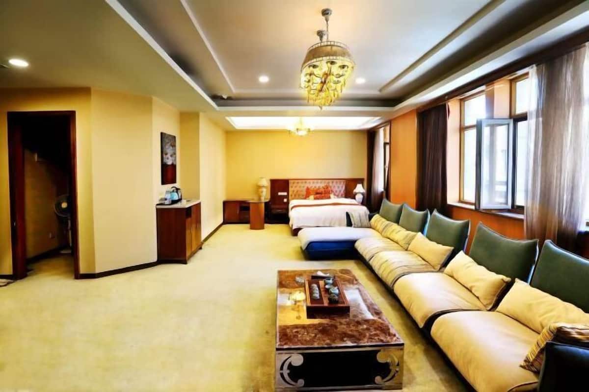 A hotel room with a sofa bed, a coffee table, a desk, and a chandelier.