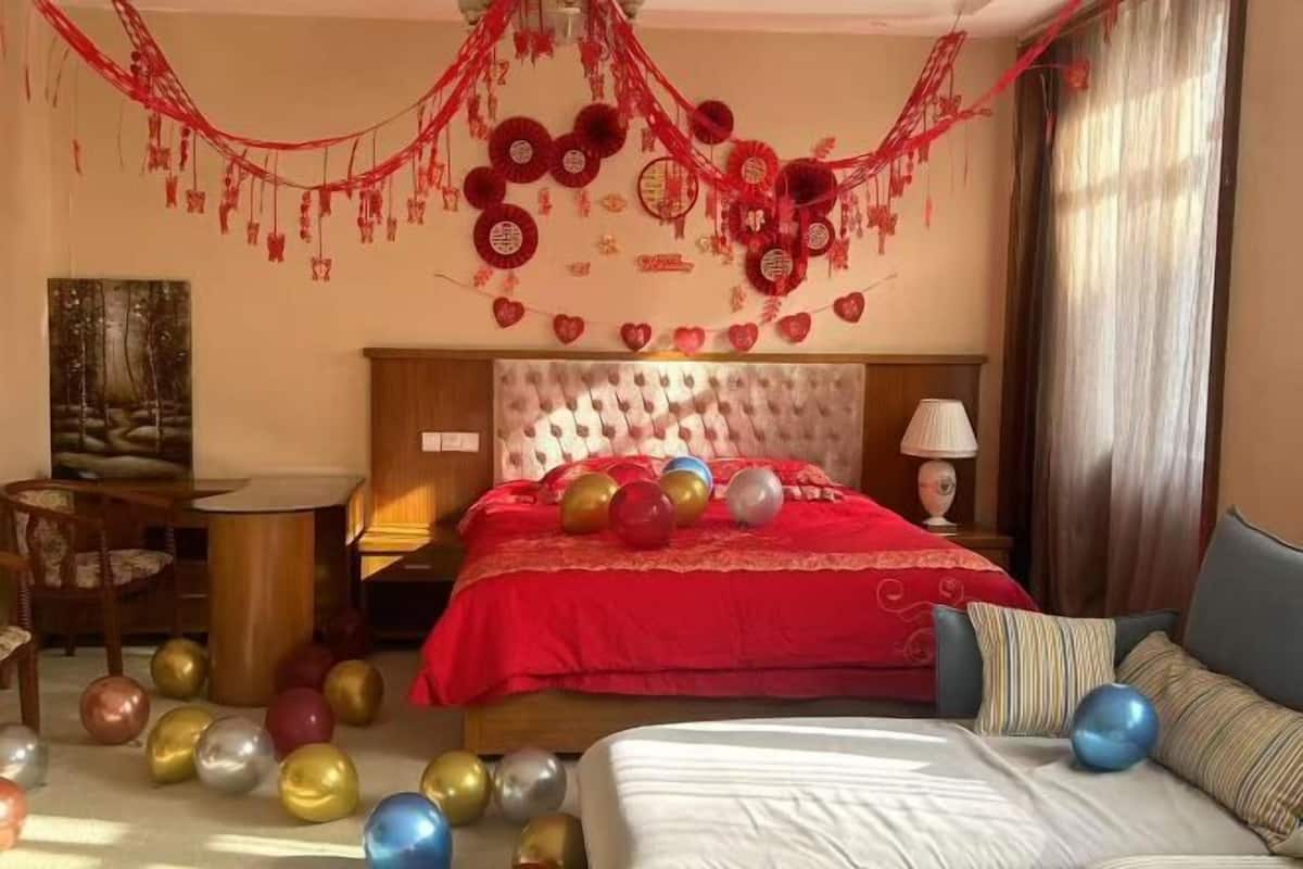 A hotel room with a large bed, a bedside table, a lamp, and a painting on the wall.