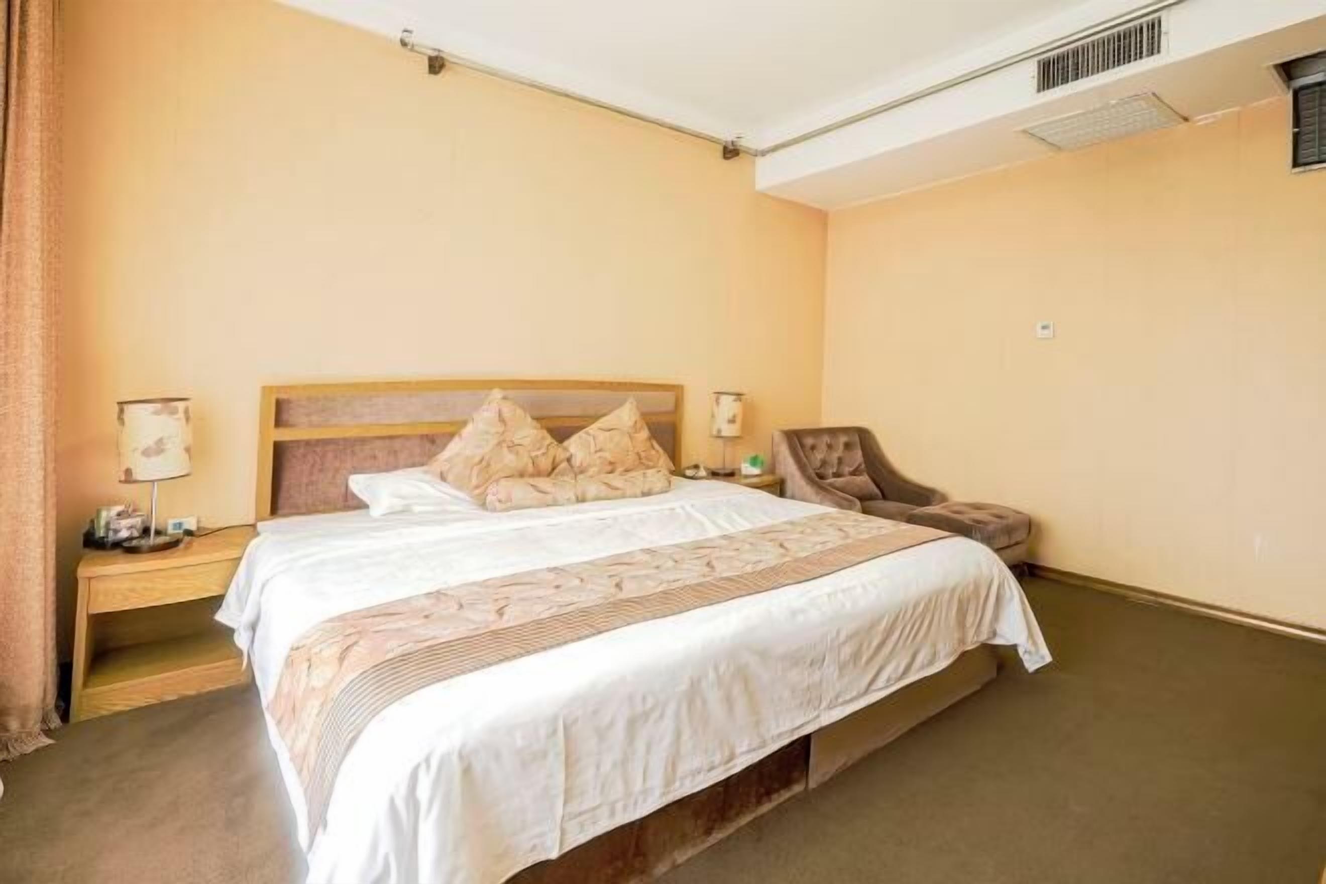 A hotel room with a bed, nightstands, a chair, and a lamp.