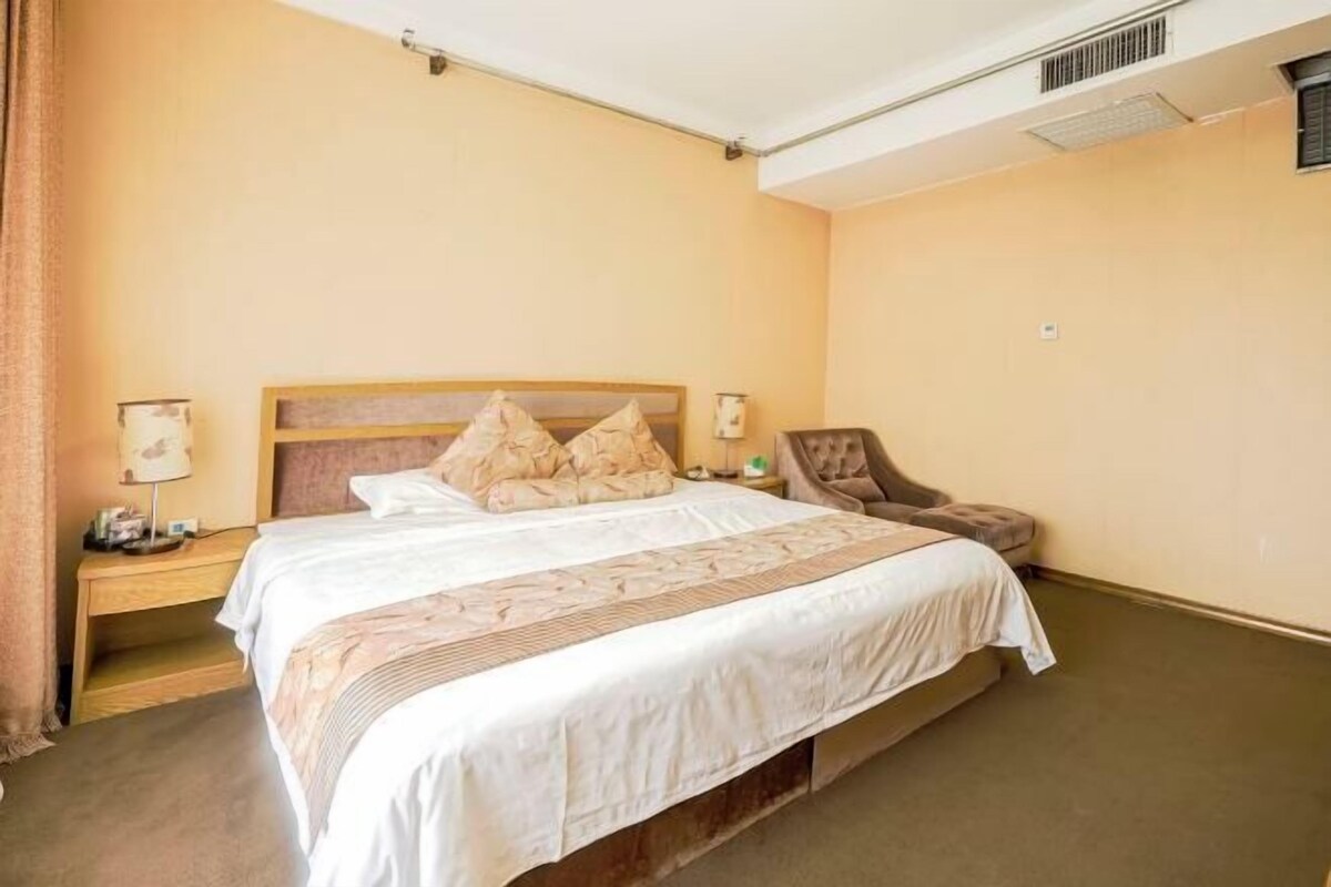 A hotel room with a bed, nightstands, a chair, and a lamp.