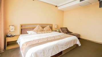 Een hotelkamer met een bed, nachtkastjes, een stoel en een lamp.