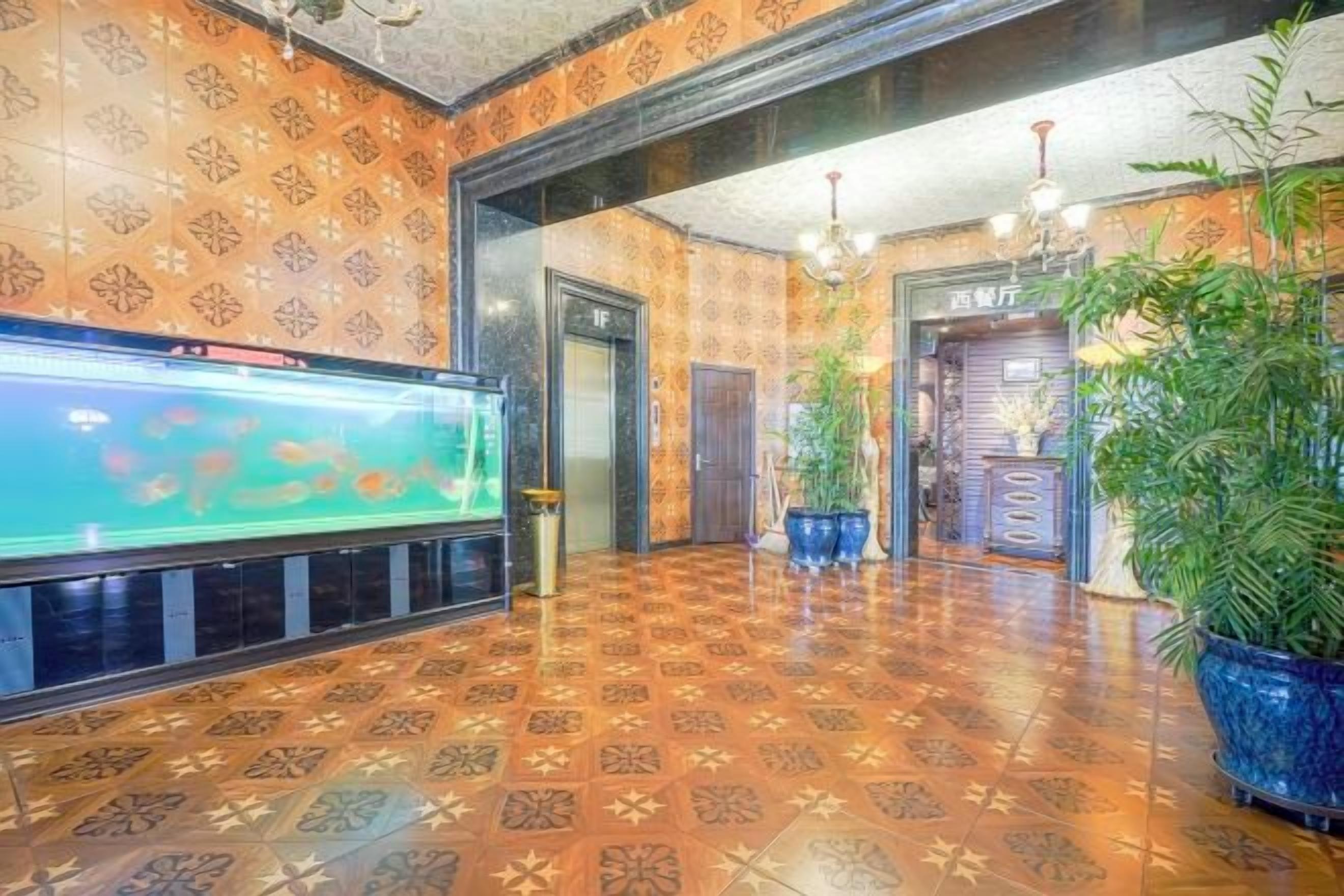 Un hall con suelo estampado, un acuario, plantas en macetas y un mostrador de recepción.