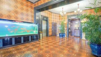 Un hall con suelo estampado, un acuario, plantas en macetas y un mostrador de recepción.
