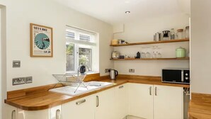 A modern kitchen with white cabinets, wooden countertops, and a window providing natural light. - Charming 4 Bedroom Home Near Oxford (Oxford)