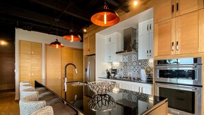 Une cuisine moderne dotée d’un îlot central, d’appareils électroménagers en acier inoxydable et d’armoires en bois.