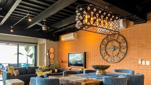 Un espace de détente moderne avec un mur en briques, une grande horloge et un luminaire suspendu.
