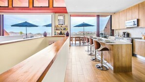 A modern kitchen with a bar area, large windows, and a view of the landscape.