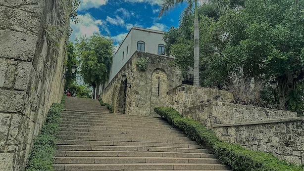 A stone staircase leading up to a building with arched windows and a flat roof.