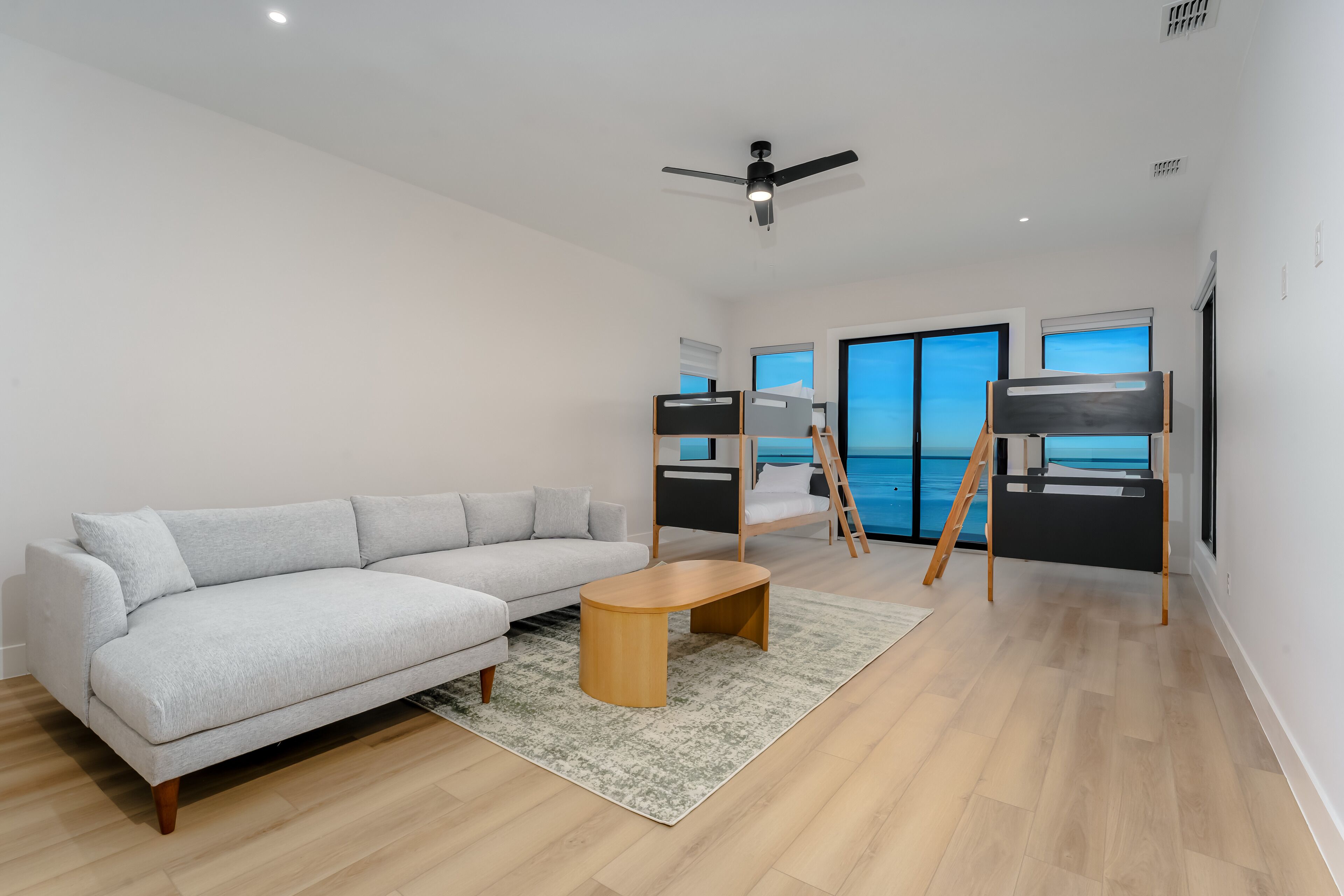 A modern living room with a light grey sofa, a wooden coffee table, and a ceiling fan.