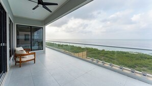 Varanda com vista para o mar, ventoinha no teto e área de estar.
