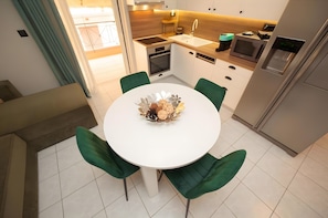 Une cuisine moderne avec une table blanche, des chaises vertes et un élément décoratif central.