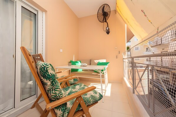 Ein Balkon mit Tisch, Stühlen und einem Ventilator.