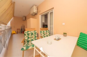 Ein Balkon mit Tisch, Stühlen und einem Blumentopf.