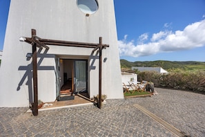 A building with a wooden cross structure, a circular window, and a paved entrance area with outdoor furniture.