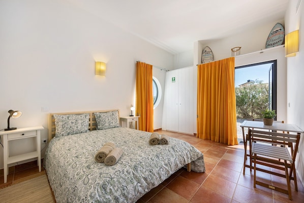 A hotel room with a bed, a desk, a chair, a window, and a view of the outside.