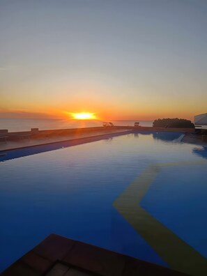 Une piscine offrant une vue sur le coucher de soleil sur l’eau.