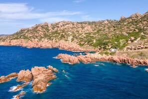 A coastal landscape with rocky cliffs and a clear blue sea.
