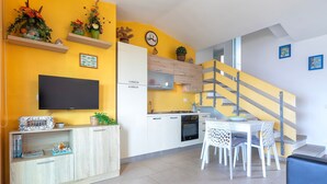 A modern kitchen with white cabinets, a built-in oven, and a dining area with a table and chairs.