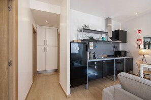 Une cuisine compacte dotée d’appareils électroménagers modernes, un coin repas avec une table et des chaises, et un espace repas séparé avec une chaise.
