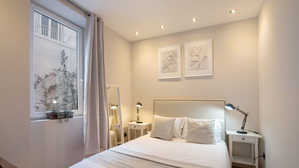 A bedroom with a bed, bedside tables, a window with curtains, and wall-mounted artwork. - Holiday Home 'Viola' with Wi-Fi and Air Conditioning (Faro)