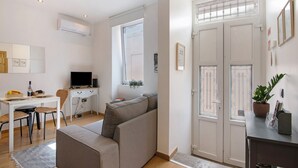A modern living room with a sofa, a desk, a television, and a potted plant. - Holiday Home 'Viola' with Wi-Fi and Air Conditioning (Faro)
