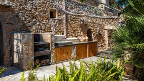 A stone building with a built-in grill and wooden cabinets. - Villa 'Es Rafal De Baix' with Sea View, Wi-Fi and Air Conditioning (Son Servera)