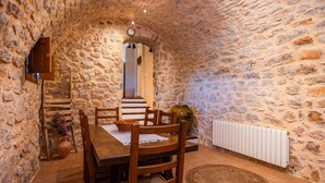 A stone-walled dining area with a wooden table and chairs, a rustic vase, and a radiator. - Villa 'Es Rafal De Baix' with Sea View, Wi-Fi and Air Conditioning (Son Servera)