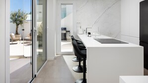 Una cocina moderna con una isla grande, taburetes de bar y vistas al patio exterior.