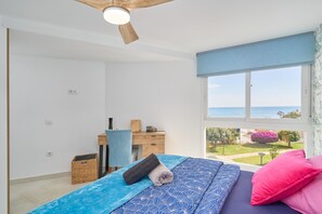 Een slaapkamer met een bed, een bureau, een stoel, een raam met uitzicht en een plafondventilator.