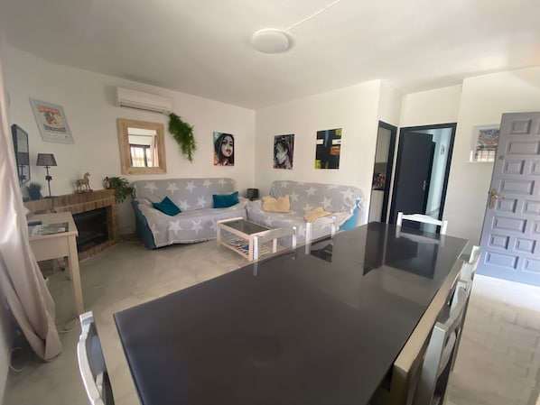 Un salon comprenant deux canapés, une table basse, une cheminée et un coin cuisine.