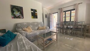 A living room with a sofa, a coffee table, and a dining area with chairs and a table.