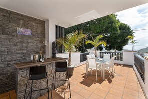 A bar area with a stone wall, bar stools, a table with chairs, and a potted plant. - Holiday Home 'Llano Del Rey' with Sea View, Private Pool & Complete Tranquility (Arona)