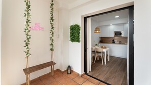 Een moderne keuken met witte kasten, een magnetron en een eethoek met een witte tafel en stoelen.