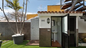 Een kleine, privé badkamer met een betegelde douche, een wastafel en een toilet.