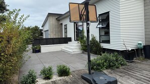 Une maison moderne avec un panier de basketball dans le jardin.