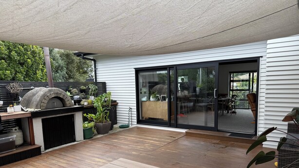 Une terrasse avec un four en pierre, une plateforme en bois et des plantes en pot.