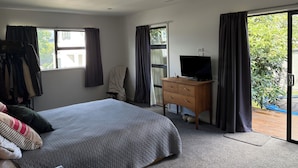 Une chambre à coucher avec un lit, une commode, un téléviseur et une fenêtre.