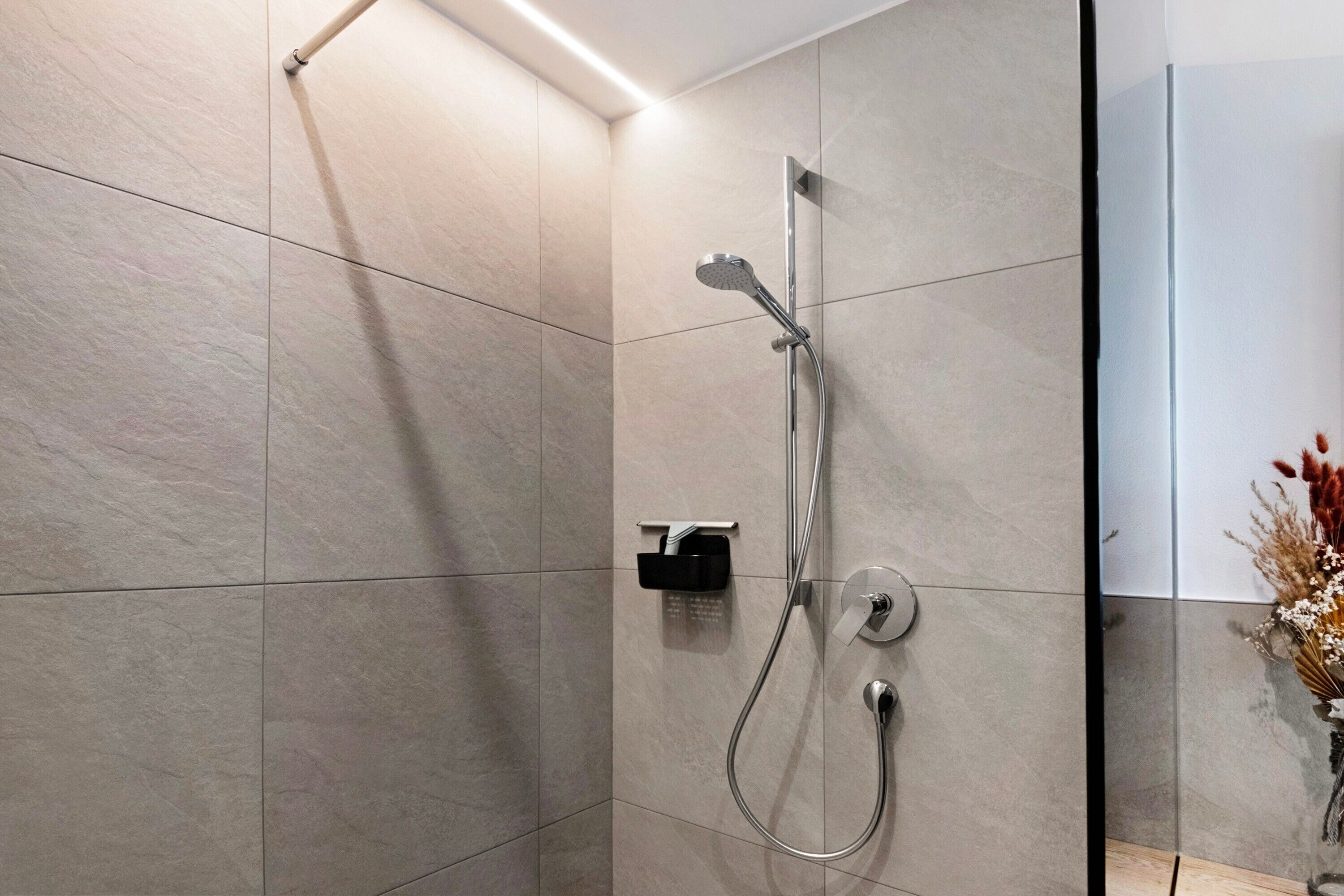 Une salle de bain moderne avec une douche, des murs carrelés et un distributeur de serviettes apparent.