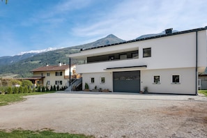 Une maison moderne à deux étages, dotée d’un garage, d’une allée et offrant une vue sur les montagnes.