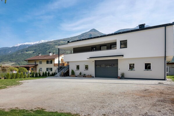 Une maison moderne à deux étages, dotée d’un garage, d’une allée et offrant une vue sur les montagnes.