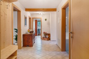 A hallway with wooden walls, a bench, a wooden dresser, and a tiled floor.