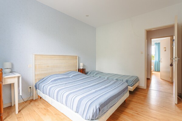 Un dormitorio con dos camas, un escritorio y una puerta que da a otra habitación.