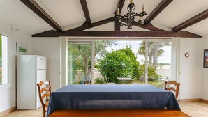 A dining area with a table, chairs, a ceiling fan, and a view of greenery outside.