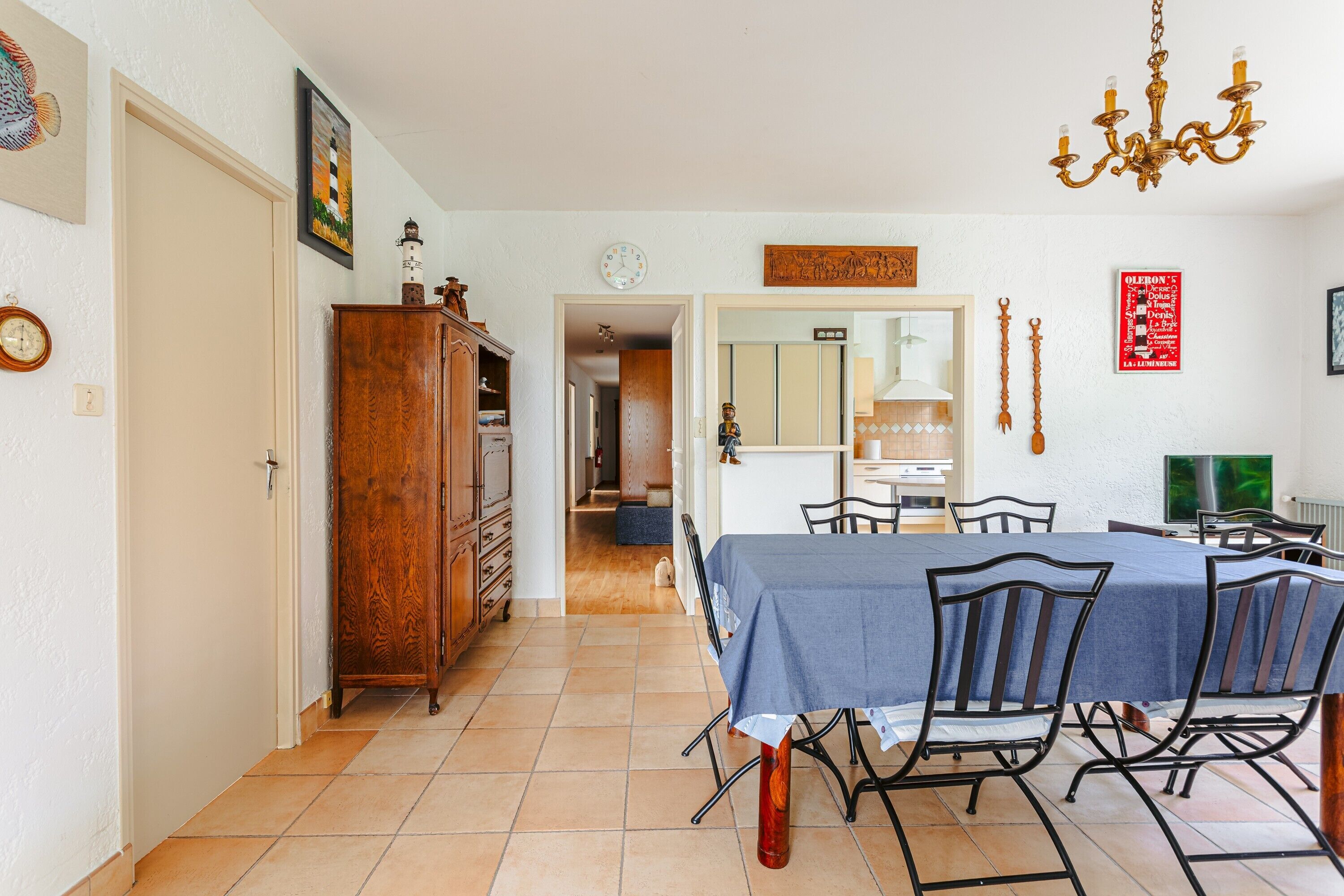 A dining area with a table, chairs, a chandelier, and a wooden cabinet.