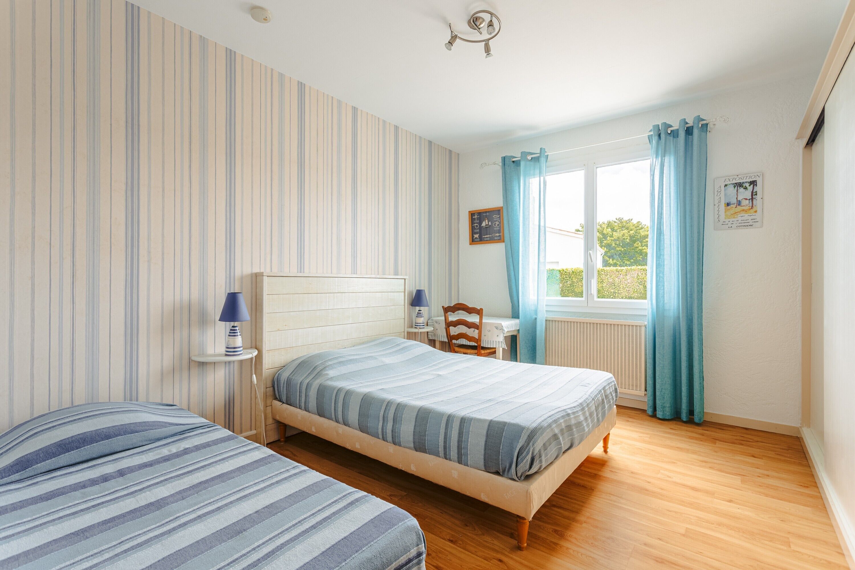 Un dormitorio con dos camas, una ventana con cortinas, un escritorio con silla y un radiador.