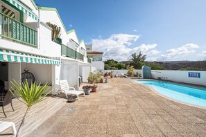 A poolside area with a pool, chairs, potted plants, and a view of the landscape. - Vacation 'Pomelo 1' with Sea View, Wi-Fi and Air Conditioning (Arguineguin)