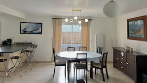 A dining area with a round table, chairs, a kitchen counter, and a cabinet. - Large family house in Fréhel | 8 guests | Ref 300 (FREHEL)