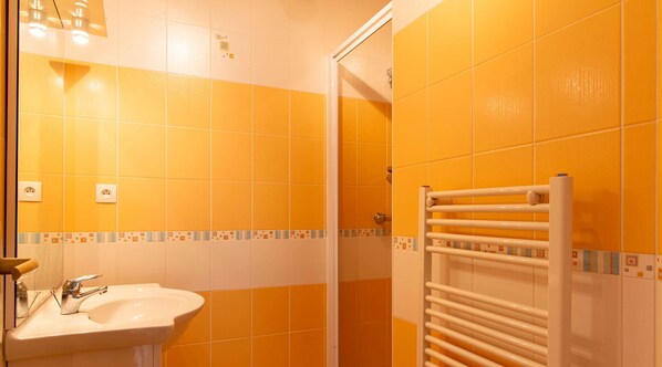 A bathroom with yellow tiles, a sink, a towel rack, and a shower area. - Large family house in Fréhel | 8 guests | Ref 300 (FREHEL)